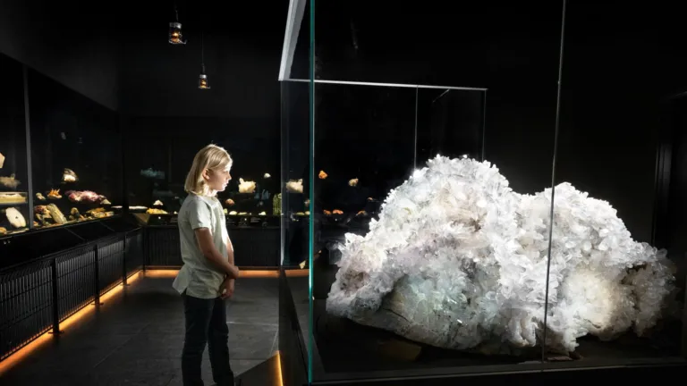 A little boy looks at a piece of rock crystal larger than himself.