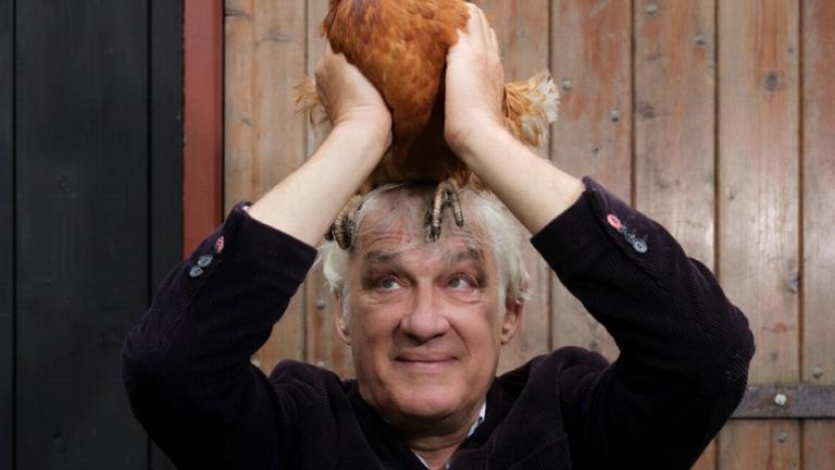 Schrijver Tijs Goldschmidt met een kip op zijn hoofd