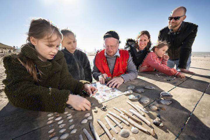 Familie telt schelpen op het strand van Katwijk