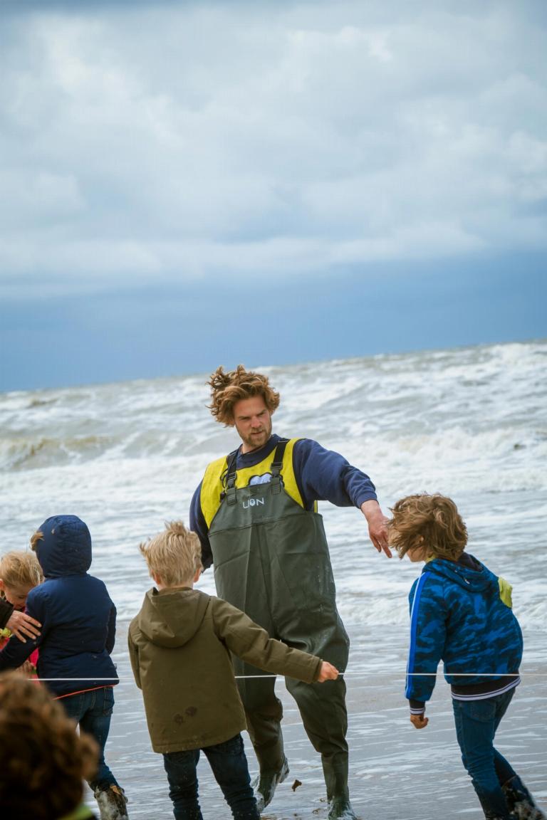 Kinderen en begeleider op het strand van Katwijk